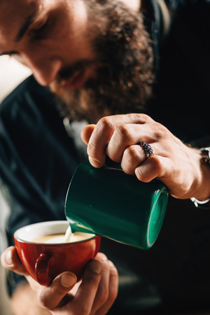 Professional barista pouring steamed milk into coffee cup making beautiful latte art.の写真素材