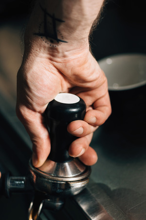 Close up image of barista hand pressing coffee using the pounder with black handle.の写真素材