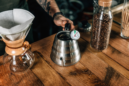 Close up of hand holding kettle with thermometer. Barista tools and equipment for making coffee.の写真素材