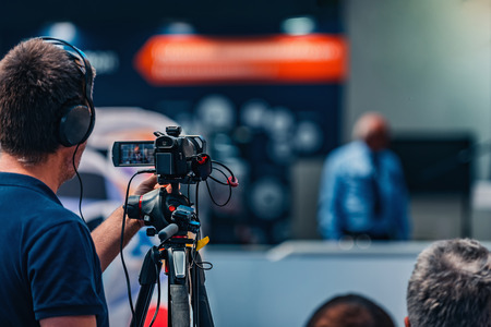 Cameraman recording male speaker wearing suit at media press conference. Live streaming concept.の写真素材