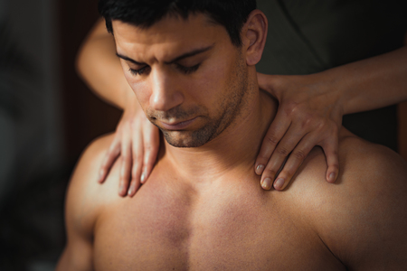 Physiotherapist massaging male patient with injured neck muscle. Sports injury treatmentの写真素材