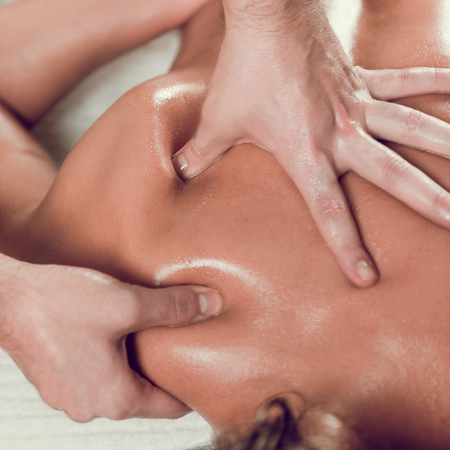 Close up of young woman with oiled skin having relaxing shoulders and back massage