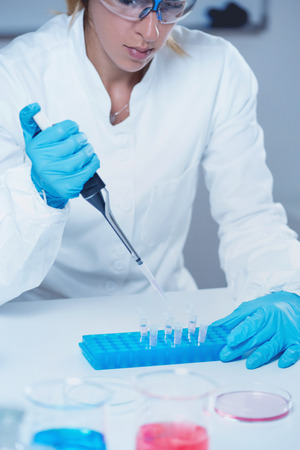 Female science researcher in laboratory, using micro pipetteの写真素材
