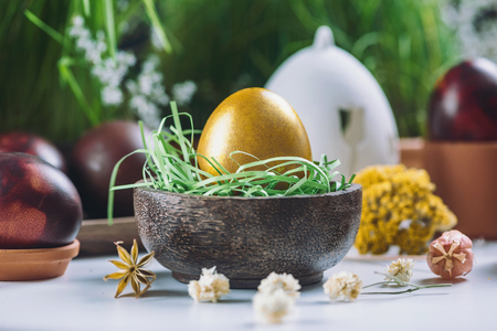 Close up image of golden Easter egg in wooden nest.  Green grass and dried flower decor. Eggs painted with onion skins. Easter holiday concept.の写真素材