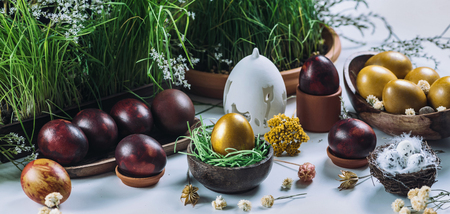 Close up image of golden Easter egg in wooden nest.  Green grass and dried flower decor. Eggs painted with onion skins. Easter holiday concept.の写真素材