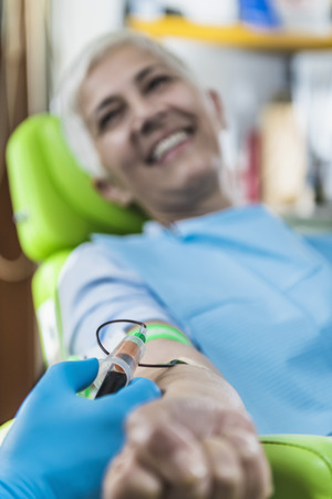 Drawing Blood for PRP face treatment. Beautiful smiling mature woman drawing blood for Platelet Rich Plasma face cosmetics treatment.の写真素材