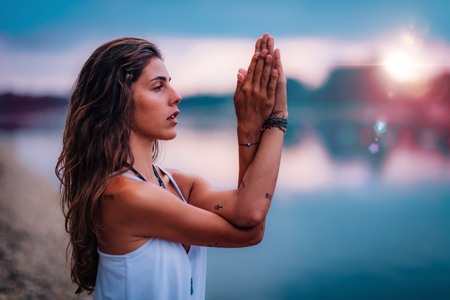 Young woman meditating. Sitting in lotus pose with hands in prayer position.の写真素材