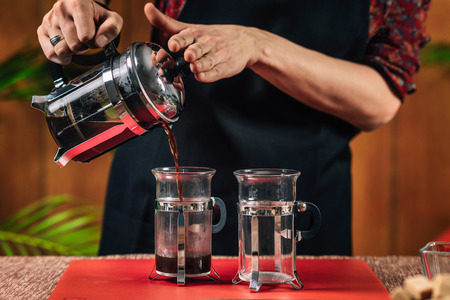 French Press Coffee. Hands of female barista pouring French press coffee in glass coffee mugの写真素材