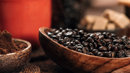 Red coffee cup, coffee beans and ground coffee in wooden bowl on table. Making coffee conceptの写真素材