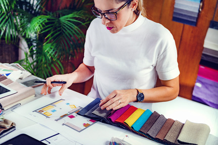 Female decorator looking at fabric samples in her office
