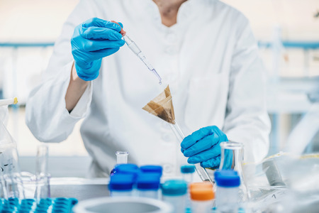 Soil Testing. Close up hands of the scientist in laboratory mixing samples of the soil with reagent.