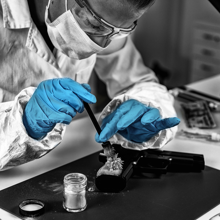 Forensic technician examining weapon, looking for fingerprints. Forensic Science Laboratory.の写真素材