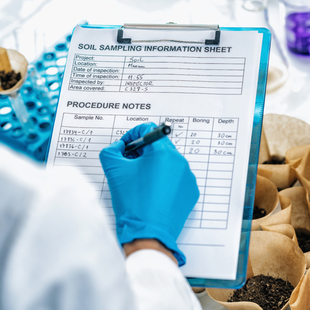 Soil Samples Testing Laboratory. Close up image of female scientist wearing white coat taking notes in laboratoryの写真素材