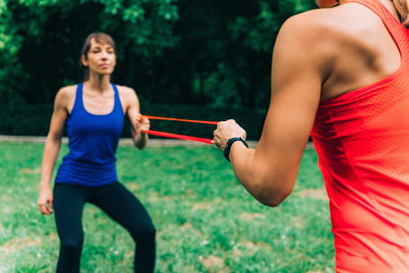 Women Exercising with Elastic Bands in a Parkの写真素材