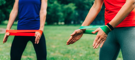 Women Exercising with Elastic Band Outdoors in the Park
