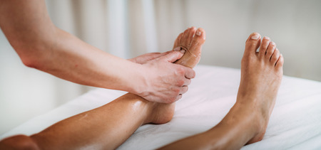 Physiotherapist massaging female patient with injured foot. Sports injury treatment.の写真素材