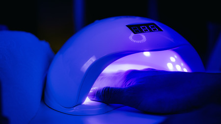 Woman Drying Nails in UV Lamp. Manicure Treatment.の写真素材