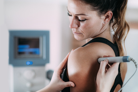 Laser therapy. Physical therapist treating patient's shoulderの写真素材