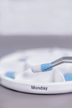 Sorting Medications. Hands sorting medication with tweezers into 7 days pill box organizerの写真素材
