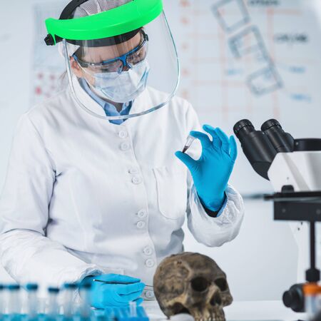 Ancient DNA Analysis. Female scientist holding micro tube with sample in ancient DNA laboratory.