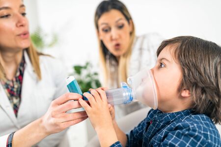 Pulmonology Doctor Helping Little Boy with Inhalerの写真素材