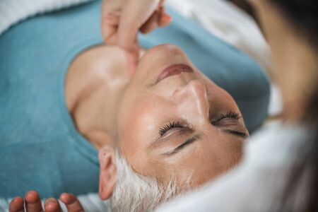 Marma therapy.  Beautiful senior woman lying on massage table and enjoying Ayurveda neck treatment....