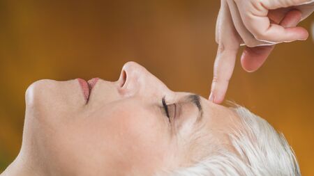 Ayurveda Marma Facial Therapy.  Marma therapy practitioner healing patient Sthapani marma, located...