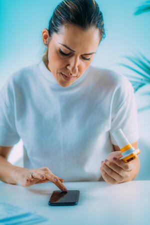 Woman Monitoring Respiratory Illness with Spirometer and Smart Phone Appの写真素材