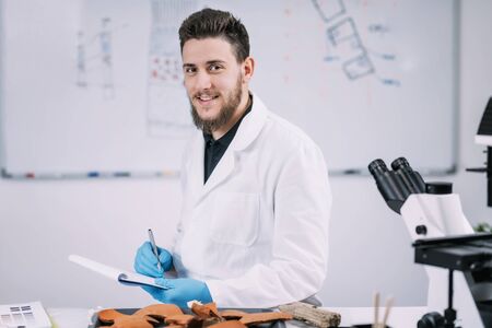 Portrait of young male archaeology student with microscope in laboratory.の写真素材