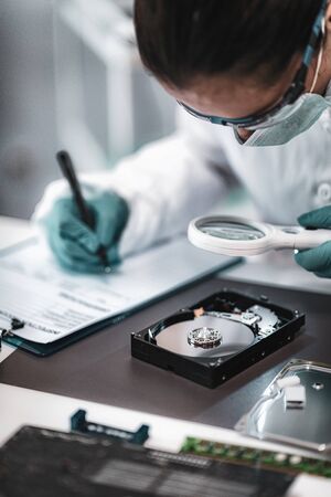 Digital Forensic Science. Police Forensic Analyst Examining Computer Hard Drive.