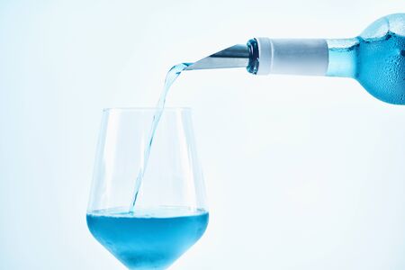 Pouring blue wine with splash and bubbles into a wine glass, close upの写真素材