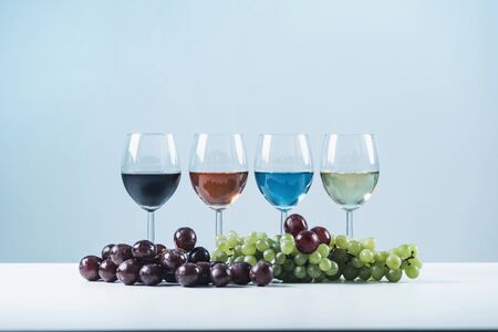 Wine Assortment. Four glasses with different types of wine and grapes on table â€“ red wine,...