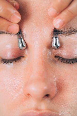 Beautiful woman receiving face massage with drainage sticks for dark circles under eyes