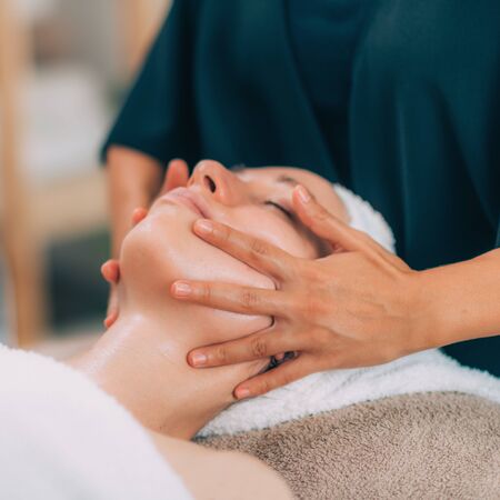 Close-up of a young womanâs face. Client receiving face lifting treatment with prayer hold technique.の写真素材