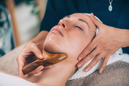 Lymphatic drainage face massage with wooden massagerの写真素材