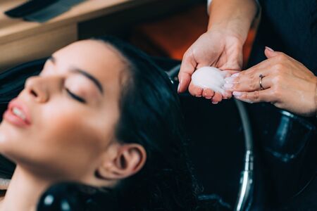 Young beautiful woman getting revitalizing hair treatment by female hairdresser in beauty salon.