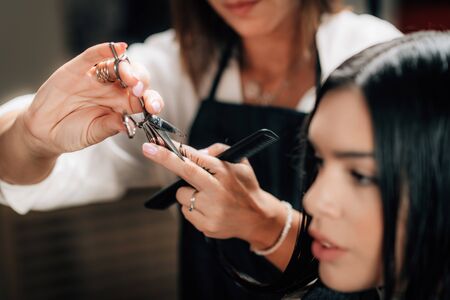 Young beautiful woman getting her hair cut by female hairdresser in beauty salon.の写真素材