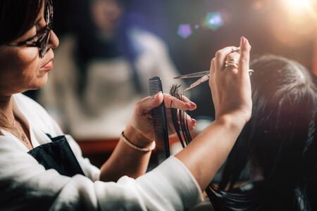 Young beautiful woman getting her hair cut by female hairdresser in beauty salon.の写真素材