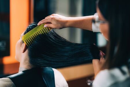 Hairdresser brushing womanâs long black hair.の写真素材