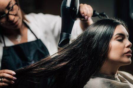 Young beautiful woman getting hair drying in beauty salon.の写真素材