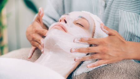 Rejuvenating Facial Mask. Cosmetologist massaging womanâ€™s face. 