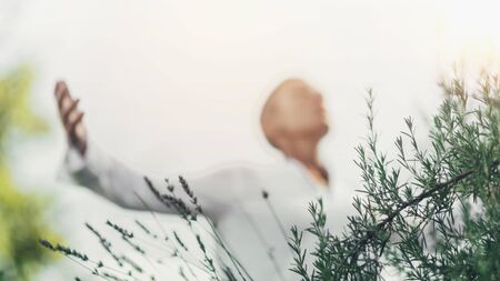 Abundance Mindfulness Concept. Middle Age Woman Expressing Positivity, Dressed in White, enjoying the scent of Rosemary.の写真素材
