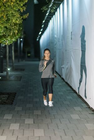 Woman Jogging at Night by the City River
