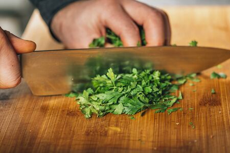 Chef holding a knife, cutting parsley on a wooden cutting boardの写真素材