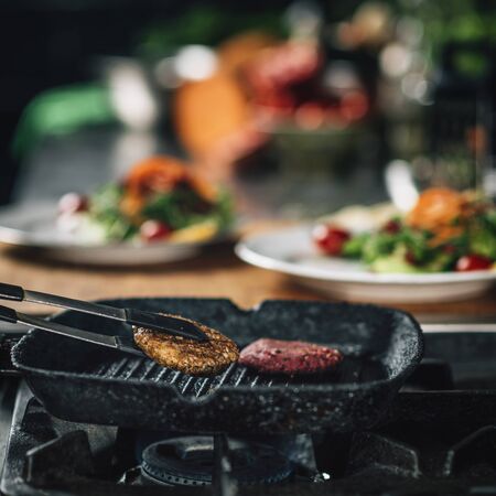 Cooking dinner in a restaurant. Close-up of a chefâs hand frying vegan burgerの写真素材
