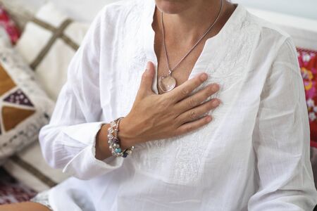 Self-Healing Heart Chakra Meditation. Woman sitting in a lotus position with right hand on heart...