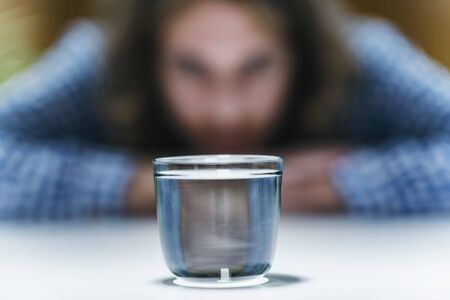 Telekinesis â€“ Young man trying to develop telekinetic powers, practicing with glass of water