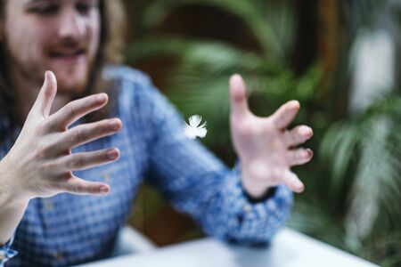 Telekinetic Power â Young man practicing telekinesis with featherの写真素材