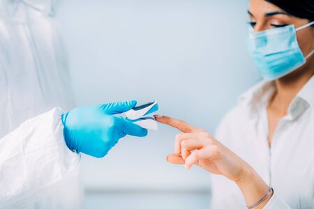 Coronavirus symptoms. Medical worker checking blood oxygen levels with oximeter, patient wearing...