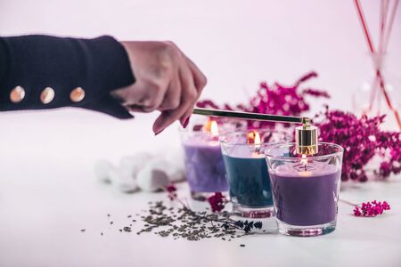 Aromatic candles. female hand extinguishing candle with golden candle extinguisher.の写真素材